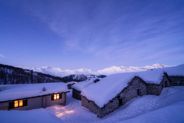 Alpine huts covered with snow at dusk, Groppera, Madesimo, Valchiavenna, Valtellina, Lombardy, Italy