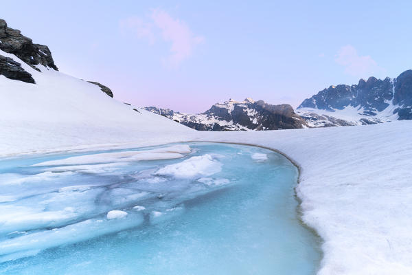 Pink sunrise over the ice melting on Forbici Lake in spring, Valmalenco, Valtellina, Sondrio province, Lombardy, Italy