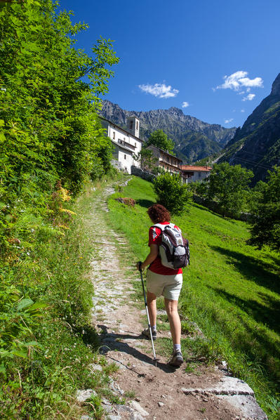 A hiker approaching the church in Val Codera, an old village in Valchiavenna, Valtellina, Lombardy Italy Europe