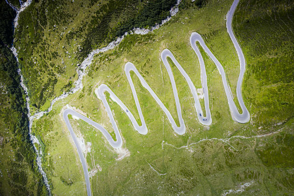Cars traveling on narrow bends of Splugen Pass mountain road, aerial view, canton of Graubunden, Switzerland