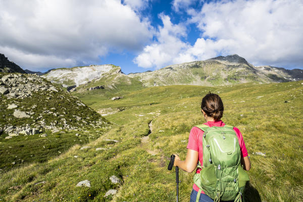 Rear view of woman with backpack and hiking poles, Pian dei Cavalli, Vallespluga, Valchiavenna, Valtellina, Lombardy, Italy