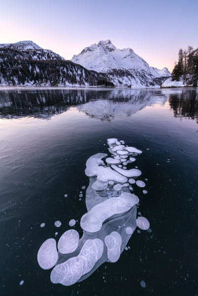 Lake Sils covered of ice bubbles with Piz Da La Margna in background at sunrise, canton of Graubunden, Engadine, Switzerland