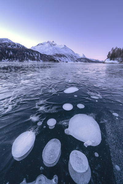 Ice bubbles in the frozen Lake Sils at dusk with Piz Da La Margna in background, canton of Graubunden, Engadine, Switzerland