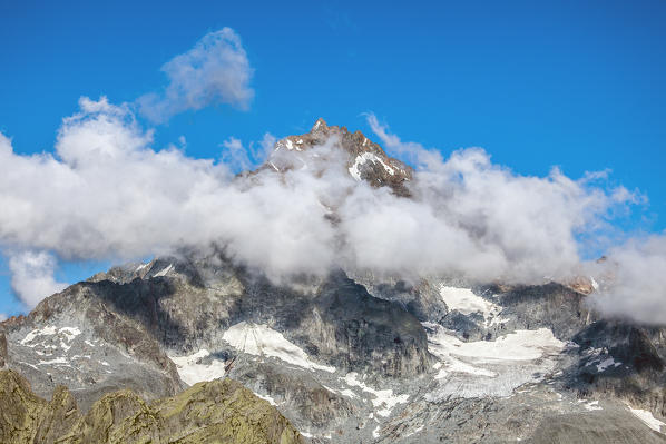 View of Monte Disgrazia sorrounded by clouds, from the side of val di Mello. Valmasino, Valtellina Lombardy, Italy Europe