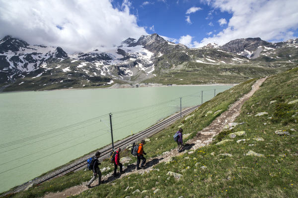 Hikers walking on the path that walks through the White Lake at Bernina Pass, where travels the Red Train of Bernina.

Bernina Pass,
Engadine,
Canton of Graubunden,
Switzerland