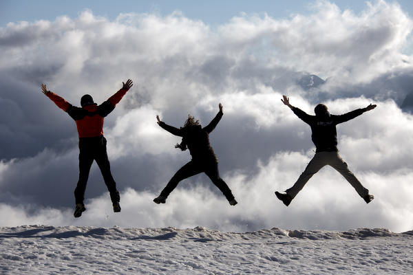 Hikers jumping in the clouds that cover the low part of the valley. Diavolezza Refuge, Engadine, Canton of Graubunden, Switzerland Europe