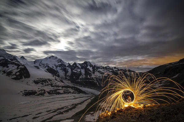Steel wool at Diavolezza refuge with full moon and Pizzo Bernina with its glaciers. Pontresina, Engadine,Canton of Graubunden, Switzerland Europe
