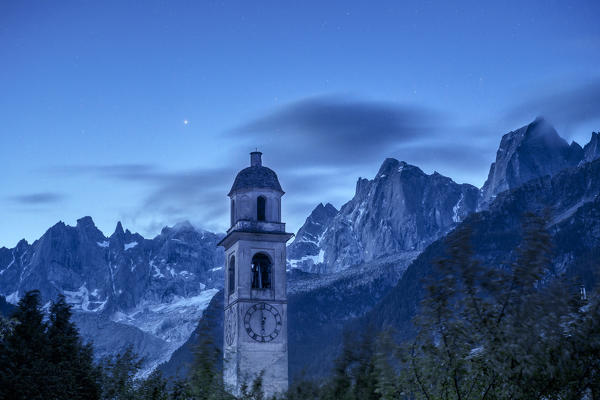 Dusk in Soglio, with an amazing view on the bell tower of the village and on the granitic peaks of Pizzo Badile and Pizzo Cengalo. Val Bregaglia, Canton of Graubunden, Switzerland Europe
