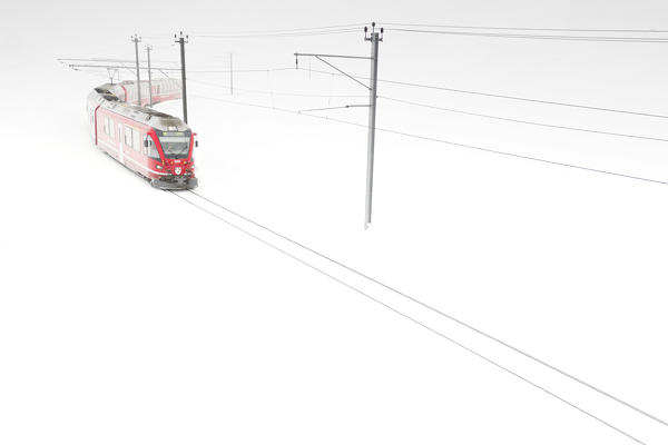 Bernina Express train in the pristine white snow at Bernina Pass during a blizzard, Graubunden canton, Engadine, Switzerland