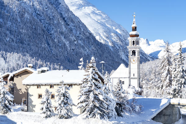 Alpine village of Bever and old church after a snow blizzard in winter, Engadine, Graubunden canton, Switzerland