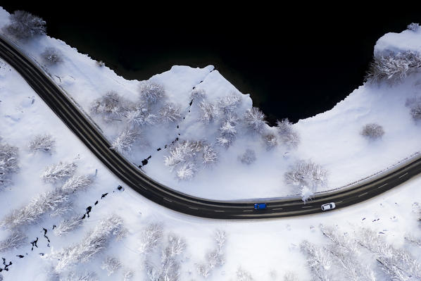 Aerial view of cars on bends of snowy road on shore of Lake Sils, canton of Graubunden, Engadin, Switzerland