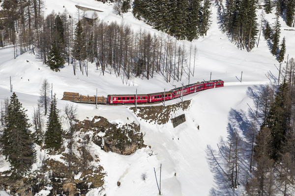 Aerial view of the red Bernina train coming from Bernina Pass in winter. Poschiavo Valley, Canton of Grisons Switzerland Europe