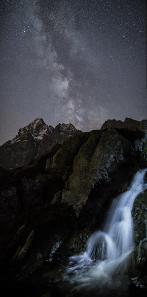 The milky way over Monviso lights up a little waterfall. Cozian Alps, Piedmont, Italy. Europe