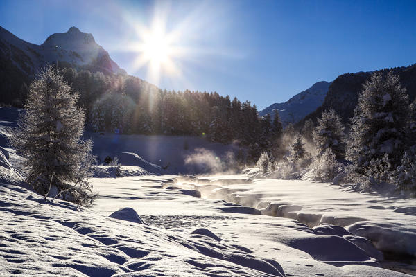 Fog rising from a creek which flows through  fresh snow Engadine. Canton of Grisons, Switzerland Europe