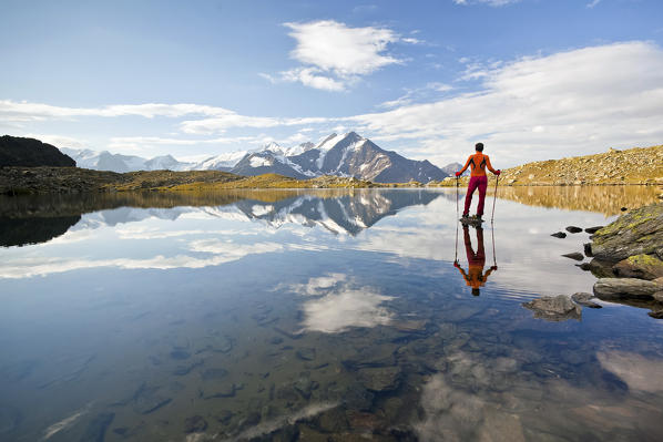 Hiker and clouds reflected in Lake Manzina. Valfurva Valtellina, Lombardy Italy Europe
