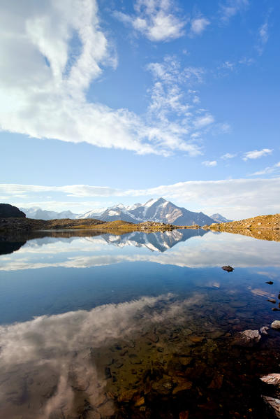 Clouds and Pizzo Tresero reflected in Lake of Manzina, Valfurva, Valtellina, Lombardy, Italy Europe