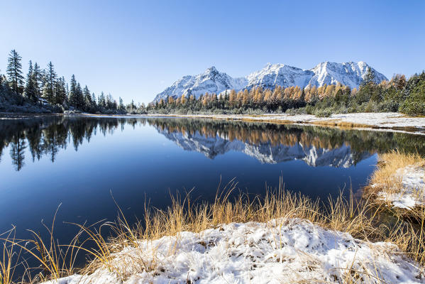 Snowy peaks are reflected in the blue water of Lake Entova in autumn Malenco Valley Sondrio province Valtellina Lombardy Italy Europe