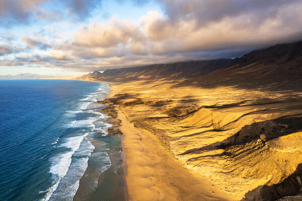 Sunset over mountains and golden sand of Cofete Beach washed by the ocean, Jandia, Fuerteventura, Canary Islands, Spain