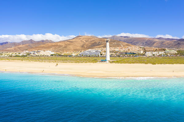 Turquoise water of the ocean surrounding the sand beach and lighthouse of Morro Jable, Fuerteventura, Canary Islands, Spain