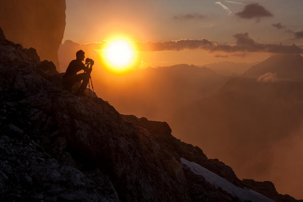 Photographer meditates in front of the sunset on the Cadini di Misurina. Dolomites, Veneto, Italy Europe