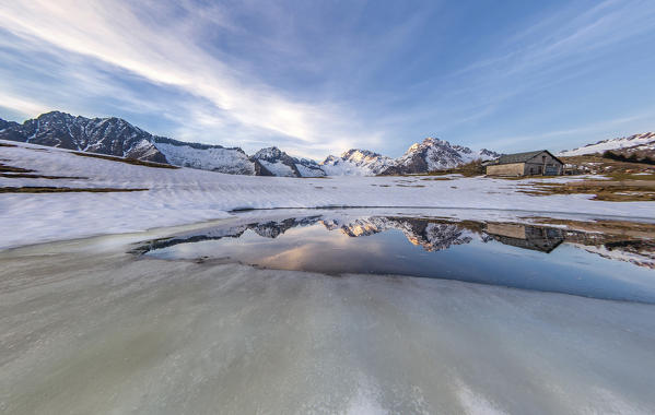 Spring sunset during the thaw at Scermendone Alp with view on Mount Disgrazia. Valtellina, Raethian Alps, Lombardy, Italy Europe