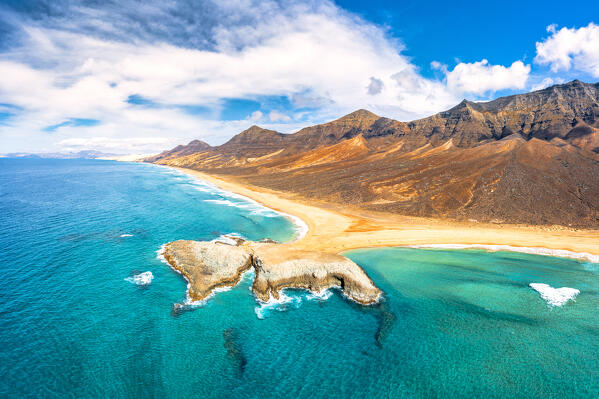 Aerial view of El Islote islet in the turquoise sea along the desert Cofete beach, Jandia, Fuerteventura, Canary Islands, Spain