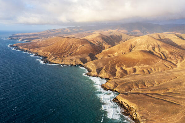 Aerial view of sunset over desert mountains and cliffs washed by ocean, Pajara, Fuerteventura, Canary Islands, Spain