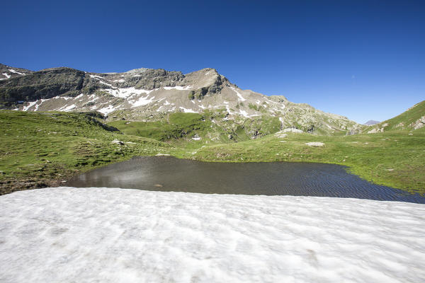Snowfield that dates back to the previous winter on the shores of Baldiscio lake. Campodolcino, Vallespluga, Valchiavenna, Lombardy, Italy Europe