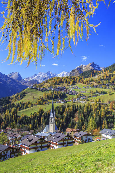 Yellow larches color the villages of Selva of Cadore and Saint Lucia hill in autumn. Dolomites. Veneto. Italy. Europe