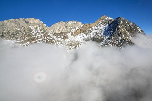 The humidity of clouds and the shadow of helicopter create Brocken spectre in Switzerland. Zermatt. Europe