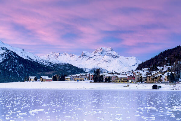 Snowy village of Silvaplana and frozen lake Champfer under the colorful sky at dawn, Graubunden canton, Engadin, Switzerland