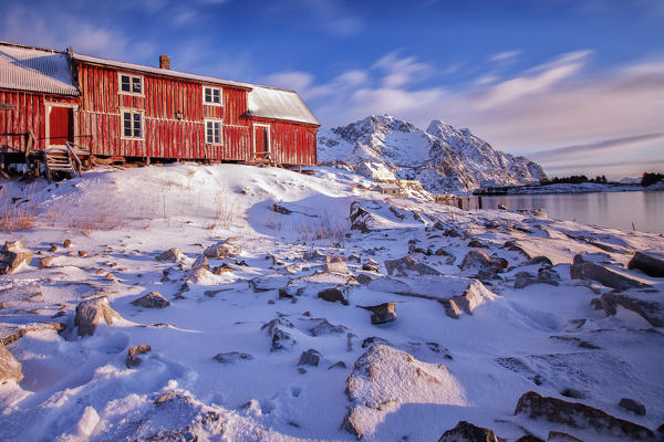 Sunlight illuminates a typical red house of Henningsvaer. Lofoten Islands. Norway. Europe