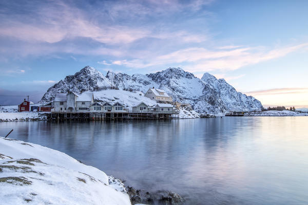 Small group of fishermen houses surrounded by snow in the harbor of Henningsvaer. Lofoten Islands. Norway. Europe