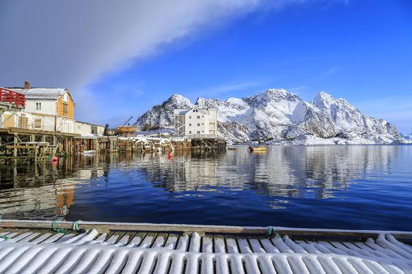 The sun illuminates the houses overlooking the port of Henninsvaer. Lofoten Islands. Norway. Europe