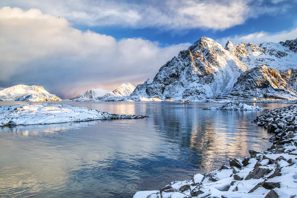 The colors of dawn light up the peaks of Henningsvaer fjord. Lofoten Islands. Norway. Europe