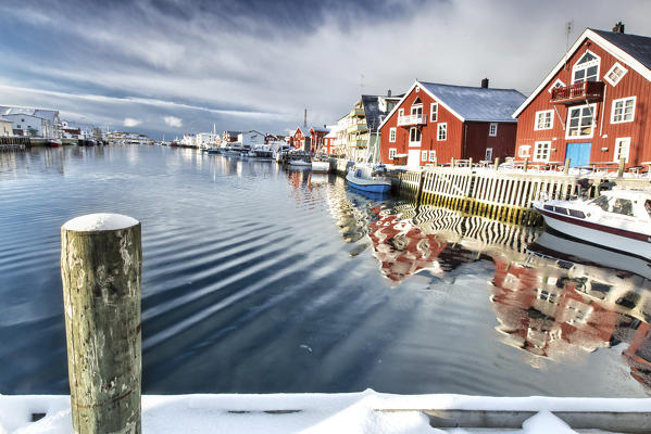 View from the pier on the channel Henningsvaer overlooked by the fishermens houses. Lofoten Islands. Norway. Europe