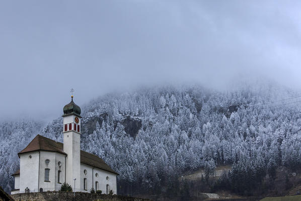 The snow has whitened the woods overlooking the Church of Wassen at San Gottardo. Andermatt. Canton of Uri. Switzerland. Europe