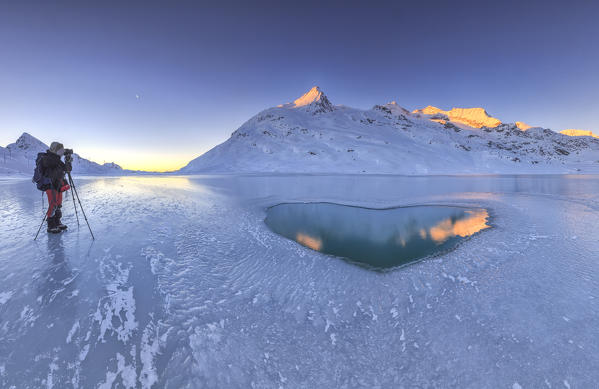 Hiker photographing a heart in the center of Lake Bianco of Bernina. Canton of Graubunden. Engadine. Switzerland. Europe