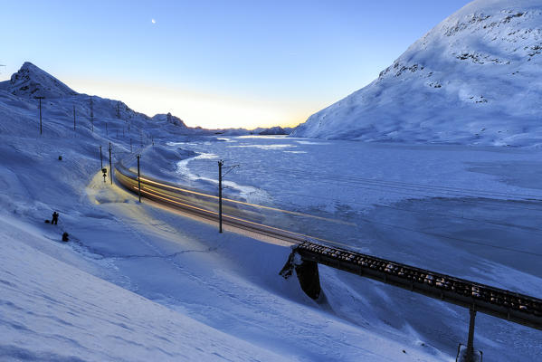 The Bernina Express Unesco Heritage passes to the Bernina Pass at dusk. Canton of Graubunden. Engadine. Switzerland. Europe