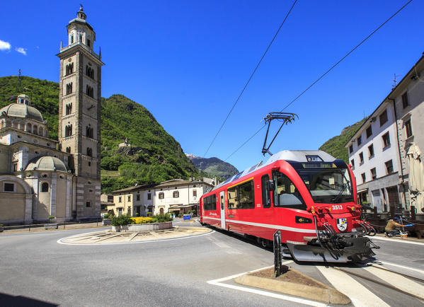 Transit of the Red Train Heritage of Unesco near the Sanctuary of the Madonna di Tirano place of pilgrimage every year to thousands of faithful. Valtellina. Lombardy. Italy. Europe
