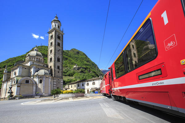 Transit of the Red Train Heritage of Unesco near the Sanctuary of the Madonna di Tirano place of pilgrimage every year to thousands of faithful. Valtellina. Lombardy. Italy. Europe
