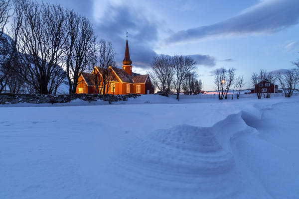 The red church of Flakstad surrounded by snow at dusk. Lofoten Islands Norway Europe