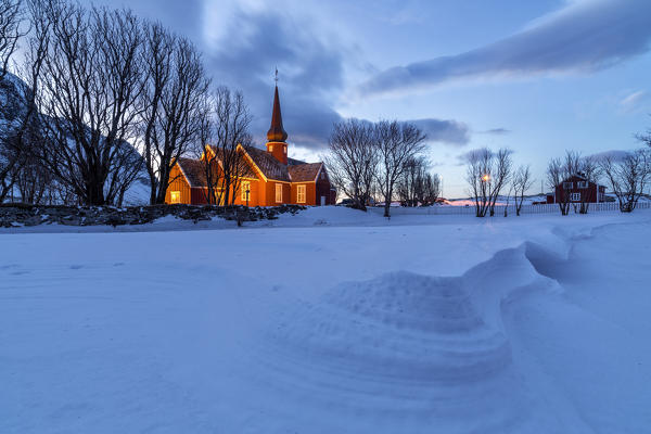 The red church of Flakstad surrounded by snow at dusk. Lofoten Islands Norway Europe
