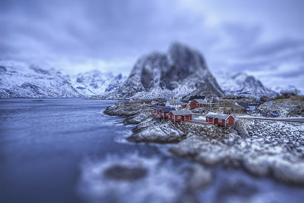 Dusk lights on the typical red houses and the rough sea. Hamnøy. Lofoten Islands Norway Europe