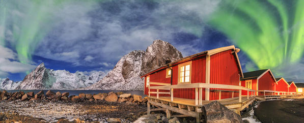 The green light of the aurora borealis lights up fishermans cabins. Hamnøy Lofoten Islands Northern Norway Europe