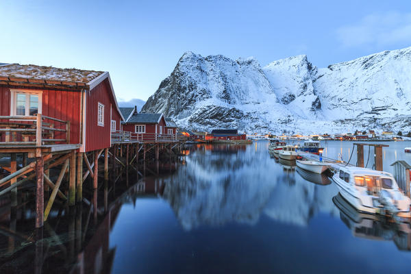 Typical red houses reflected in the sea at dusk. Reine. Lofoten Islands Northern Norway Europe
