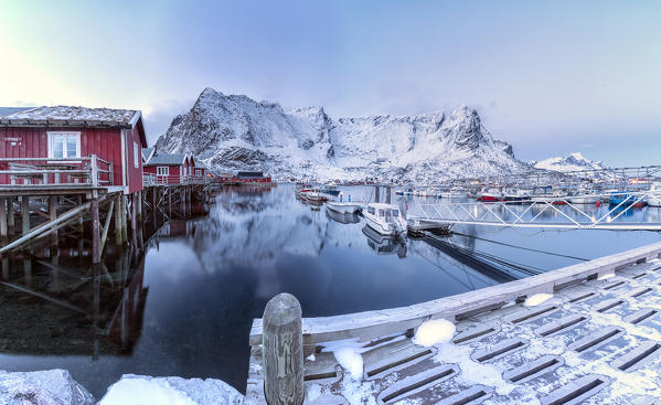 Typical red houses reflected in the sea at dusk. Reine. Lofoten Islands Norway Europe