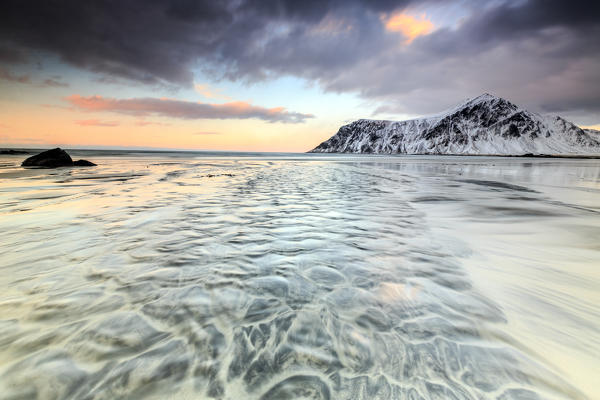 Waves on the  surreal Skagsanden beach surrounded by snow covered mountains. Lofoten Islands Northern Norway Europe