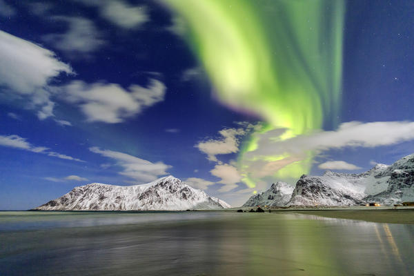 Northern Lights illuminate Skagsanden beach and the snowy peaks. Lofoten Islands Northern Norway Europe