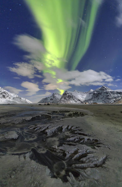 Northern Lights illuminate Skagsanden beach and the snowy peaks. Lofoten Islands Northern Norway Europe